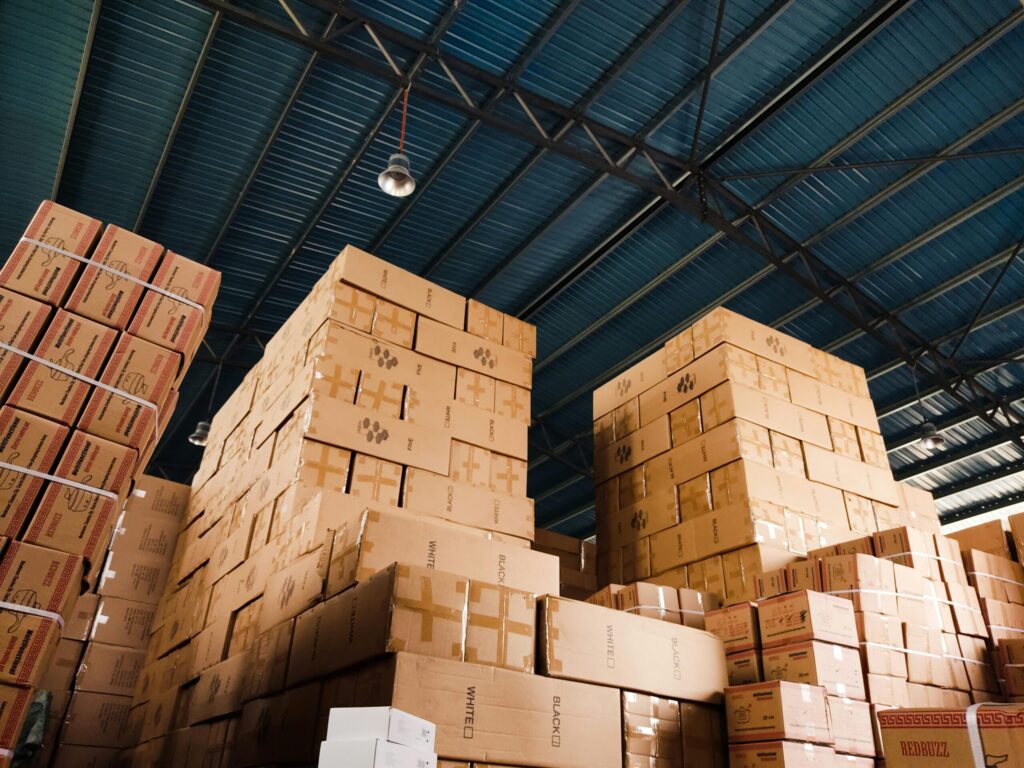 High stacks of cardboard boxes organized in a warehouse with a blue metal ceiling.
